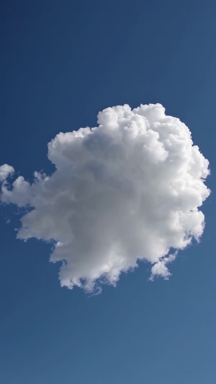 A single fluffy cloud floats against a clear blue sky, captured from a low-angle perspective