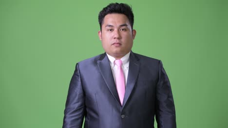 초록색 배경에 젊은 잘생긴 과체중 아시아 사업가