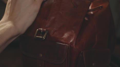 applying wax to the upper body of a tan leather vintage backpack using a clean sponge - closeup shot