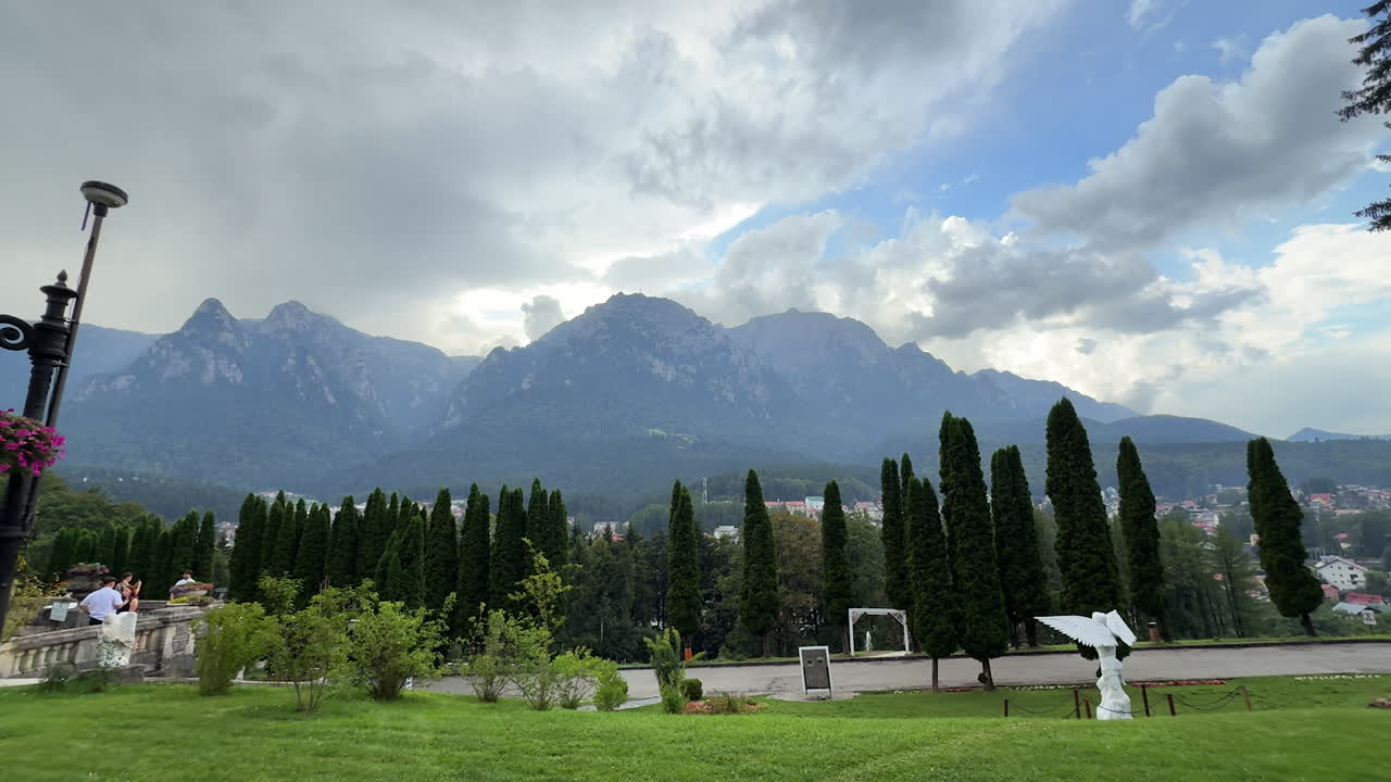 Tour by the territory of the beautiful Cantacuzino Castle, Bu?teni, Romania on a rainy day. Mountains under the grey cloudscape at backdrop