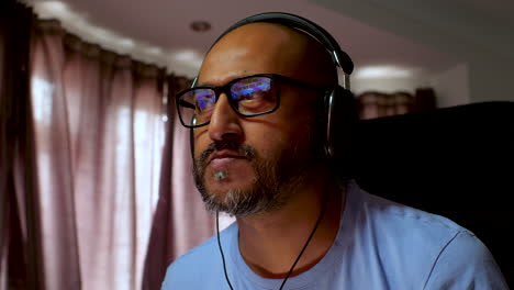 South-Asian-man-working-from-home-wearing-glasses-and-headphones