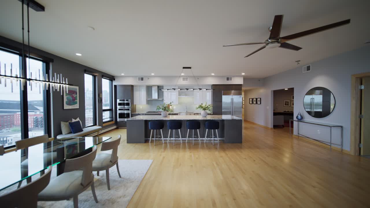 Wide push in shot of an open concept luxury kitchen and dining area with floor-to-ceiling windows and hardwood floors