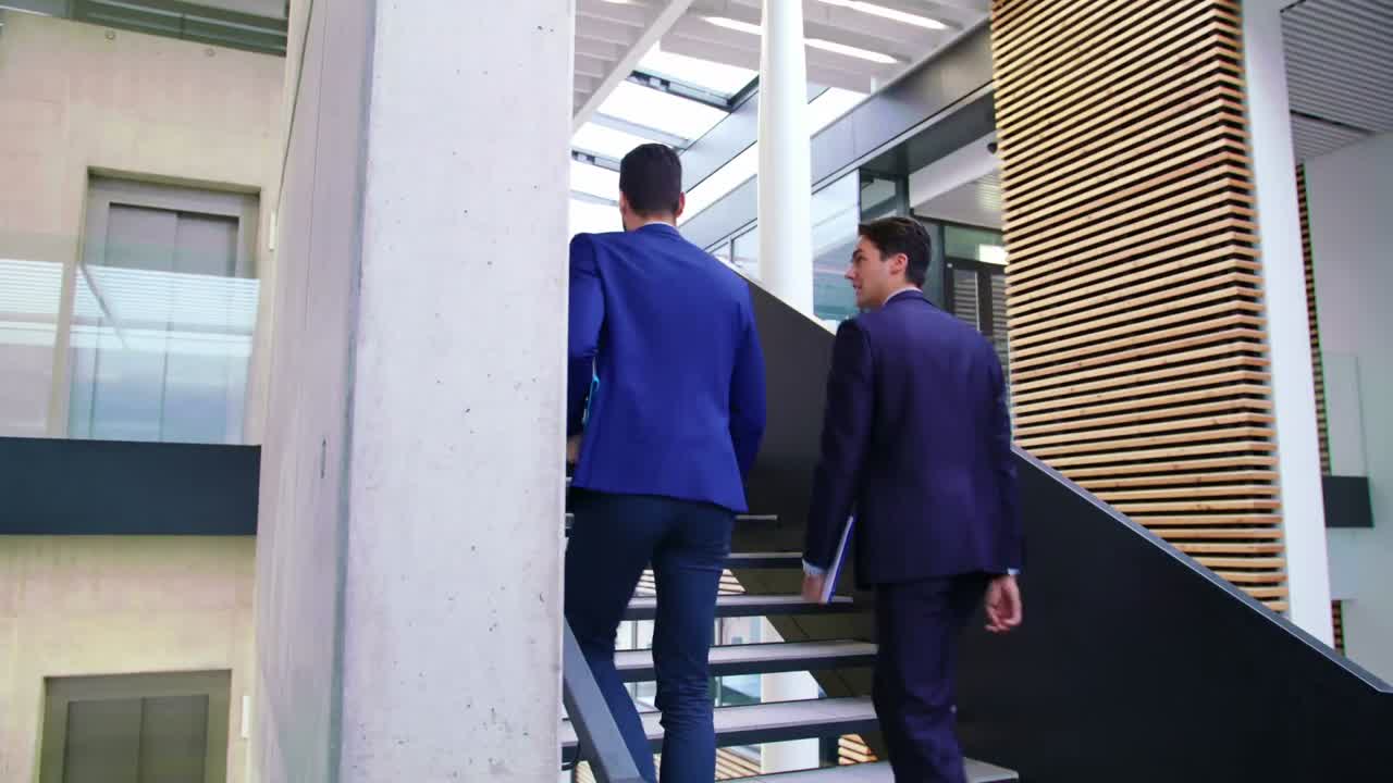 hombres de negocios interactuando entre sí mientras caminan por las escaleras