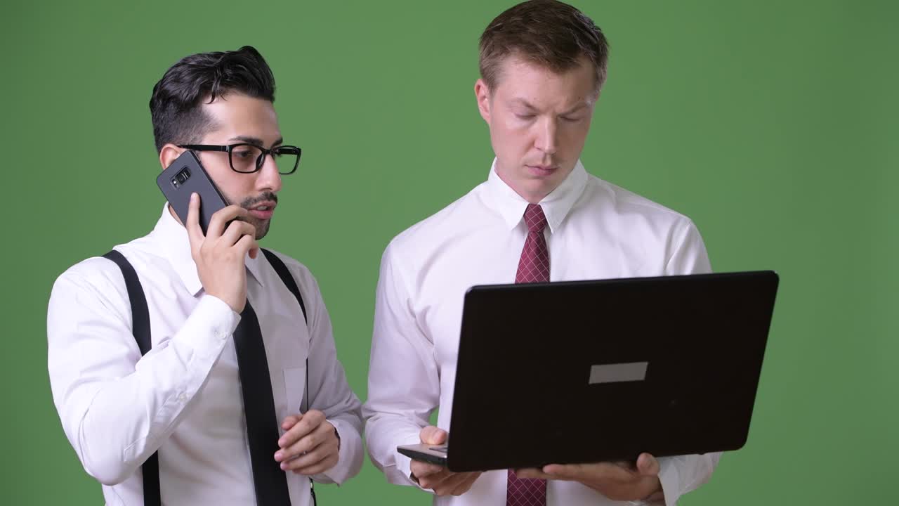 dos jóvenes empresarios multiétnicos trabajando juntos contra un fondo verde