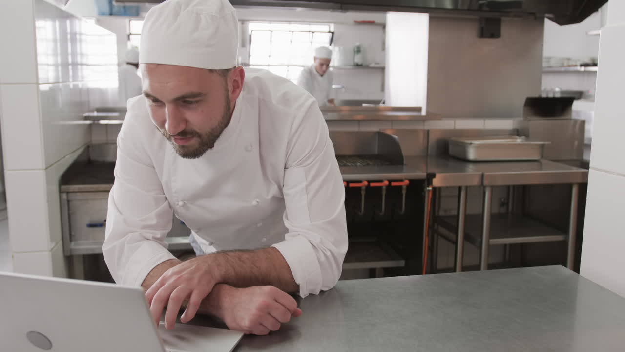 Chef maschio caucasico che usa il laptop in cucina, al rallentatore