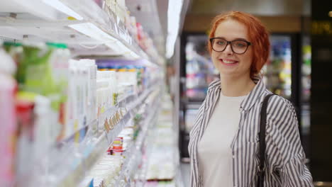 Kaukasische-Junge-Frau-Wählt-Milch-Und-Lächelt-In-Die-Kamera-In-Einem-Supermarkt