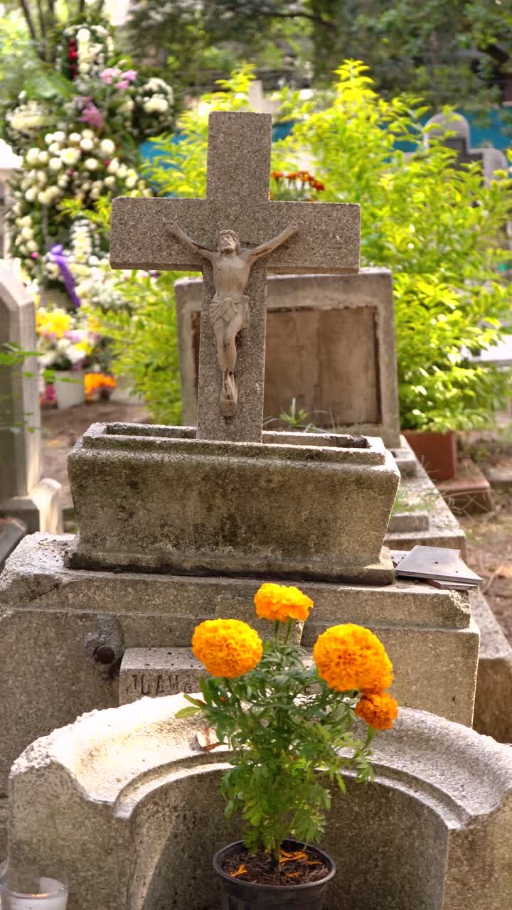 Crocifisso e vaso di fiori cempasúchil su una tomba in formato verticale