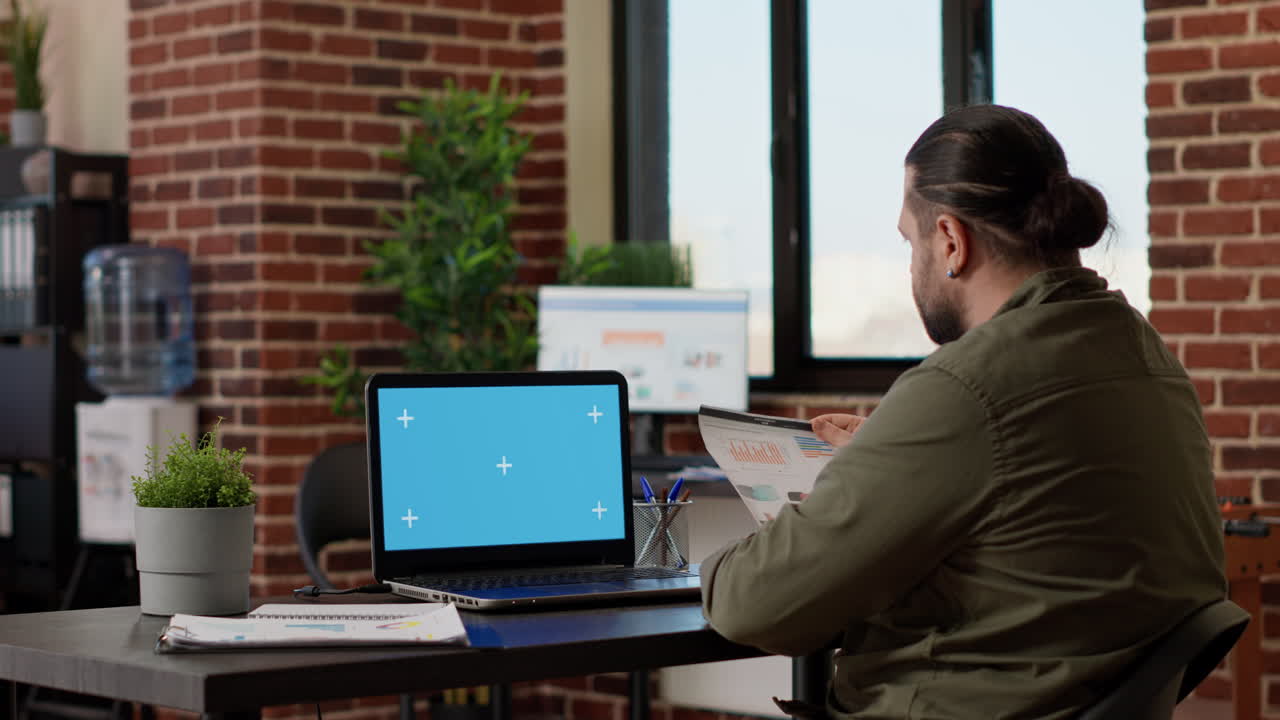 Office worker using laptop with greenscreen display at job