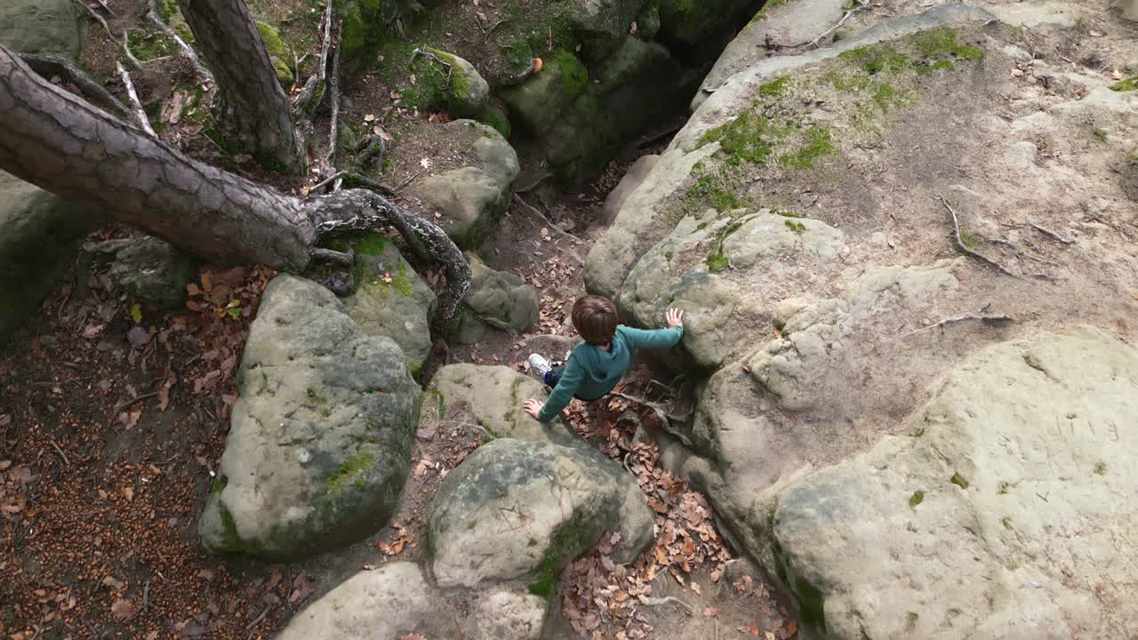 niño pequeño entra en una grieta de roca. vista de arriba hacia abajo