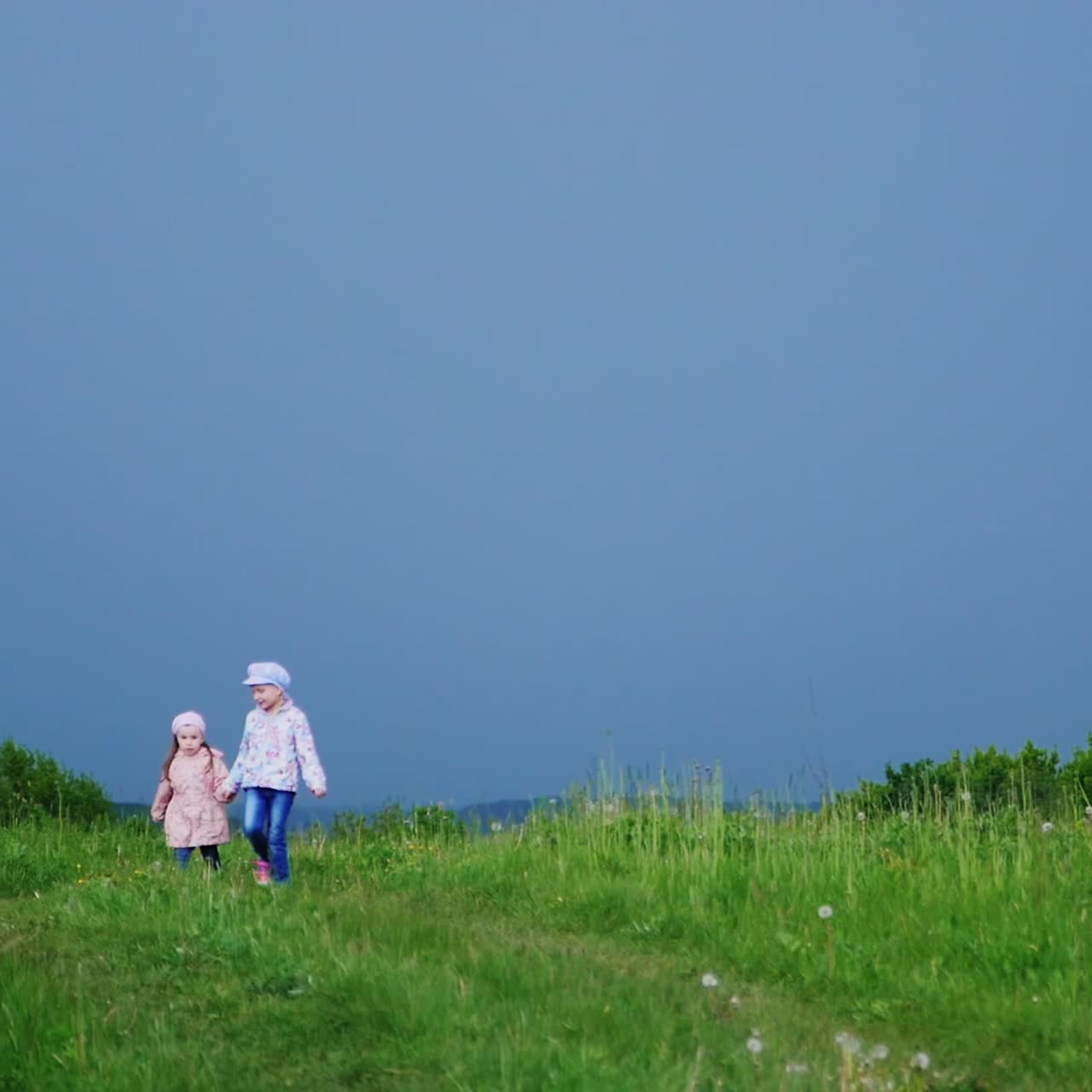 두 명랑한 소녀가 손을 잡고 초원을 뛰어다닌다 3