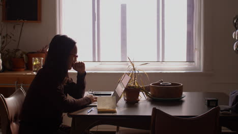 Profile-shot-of-a-woman-typing-on-a-keyboard-as-she-works-from-home-on-a-laptop