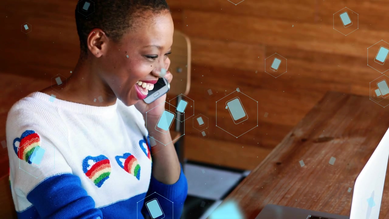 Donna che digita al laptop, con icone di telefono blu fluttuanti, nota un avviso, prende e risponde a una chiamata, sorridendo