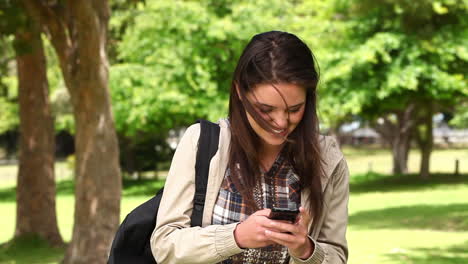 Mujer-Riendo-Mientras-Lee-Un-Mensaje-De-Texto-En-Su-Teléfono-Móvil