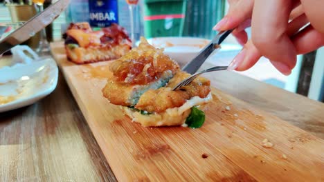 Cut-delicious-chicken-sandwich-with-knife-on-wooden-board,-close-up-view