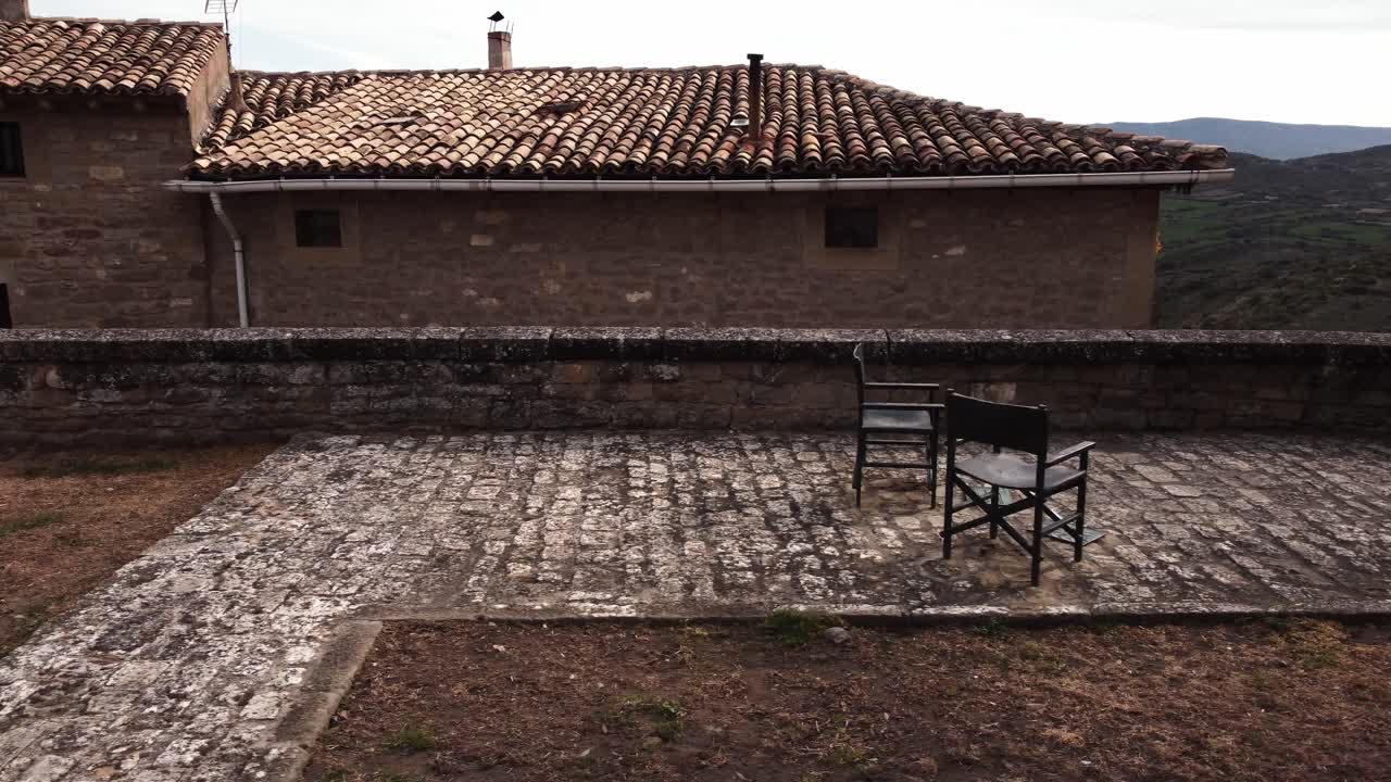 Ground-level shot panning left to right showing a sculptural tribute of metal chairs to filmmaker Berlanga in Sos del Rey Católico.