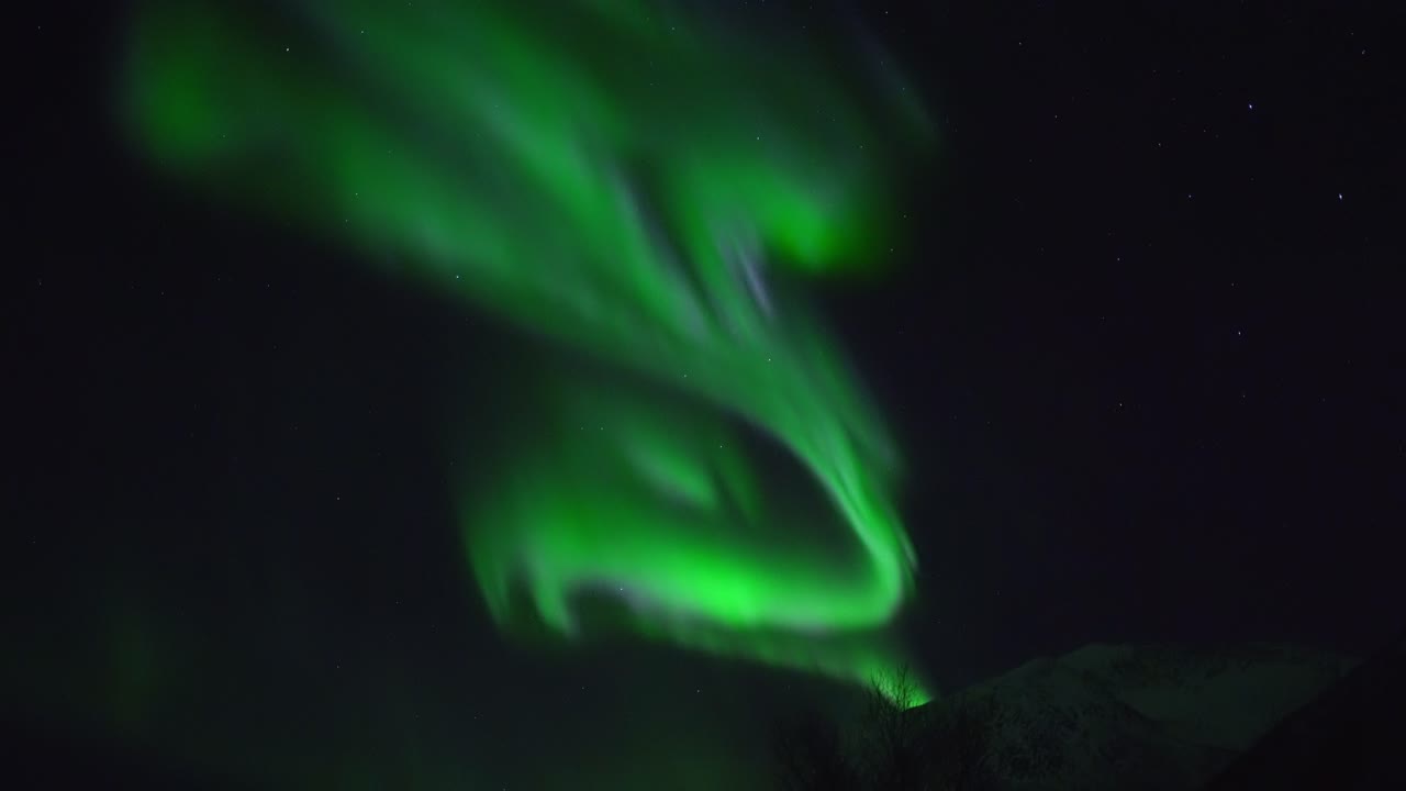 la aurora boreal filmada en tiempo real sobre el paisaje montañoso en la isla kvaløya cerca de tromsø en el norte de noruega