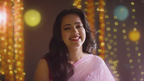 portrait of smiling asian woman celebrating diwali against bokeh lighting background