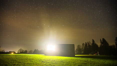 Impresionante-Lapso-De-Tiempo-Del-Cielo-Nocturno-Con-Un-Brillo-Claro-Que-Comienza-A-Girar-Y-Los-Disparos-Comienzan-A-Volar-Por-El-Cielo-En-Un-Bosque-Con-Un-Cobertizo