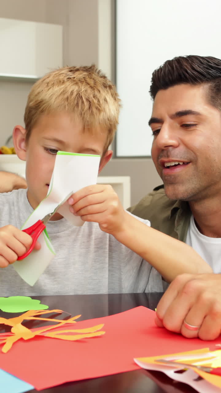 padre y hijo felices haciendo artes y artesanías en la mesa de la cocina