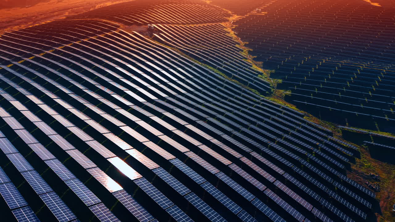 Campi collinari con molteplici celle fotovoltaiche moderne. Il sole al tramonto illumina il paesaggio. Prospettiva aerea.
