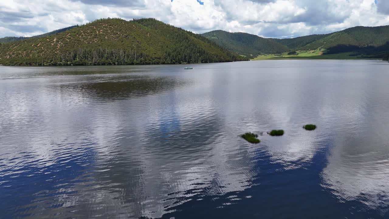 A peaceful aerial shot of a vast mountain lake with clear water reflecting a dramatic cloudy sky, ideal for travel and nature documentaries