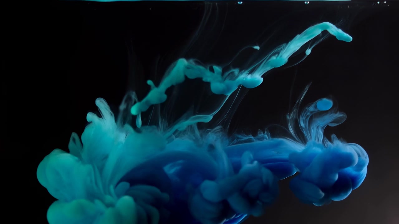 Primo piano cinematografico di inchiostro ciano che entra in un liquido scuro dalla superficie superiore, rompendo una stretta colonna lucida in nastri affusolati, goccioline sospese e formazioni dense.