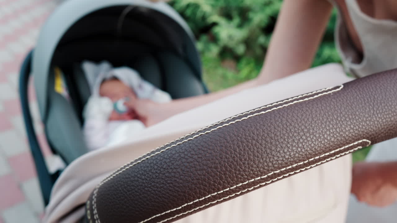 Close up of a mother placing a pacifier into a baby's mouth while seated in a stroller