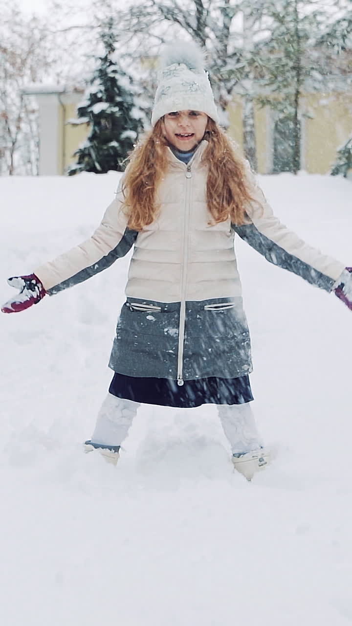Happy girl playing in snow. Vertical video