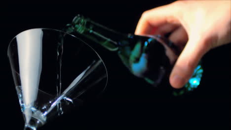 hand pouring blue alcohol into cocktail glass