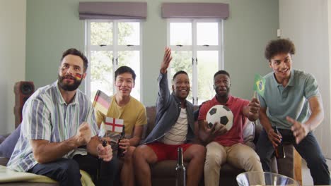 happy diverse male friends watching tv and drinking beer in living room