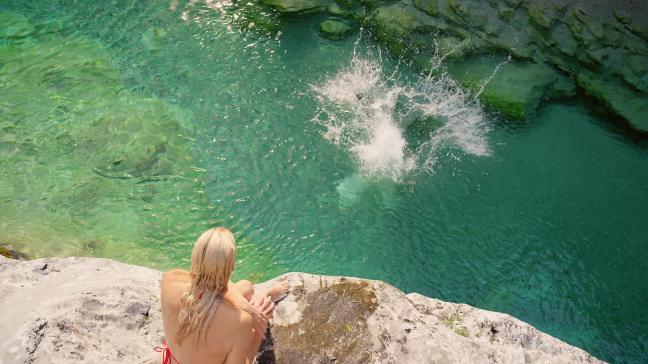 dos amigas emocionadas nadando en un lago después de saltar de un acantilado. dos mujeres en bikini buceando desde un acantilada para nadar en un lago. mujeres de vacaciones juntas saltando a un lago desde un acanal para nadar