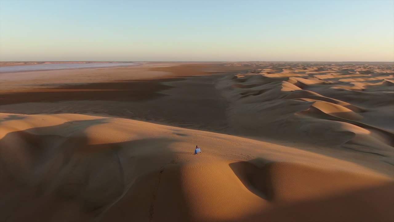 Aerial view of a lonely woman exploring the vast and arid dunes of the Sahara desert in Morocco