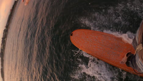 vertical shot of a surfer riding on a surfboard on the sea