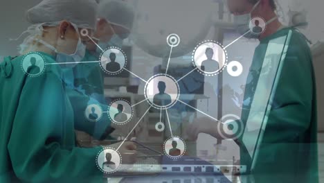 Animation-of-network-of-connections-with-icons-over-hands-using-laptop-and-diverse-surgeons