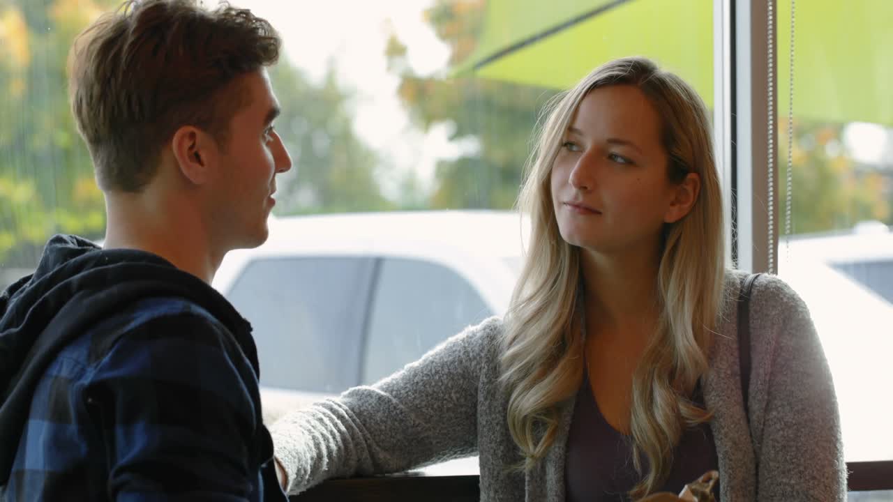 una joven pareja interactuando entre sí en un café 4k