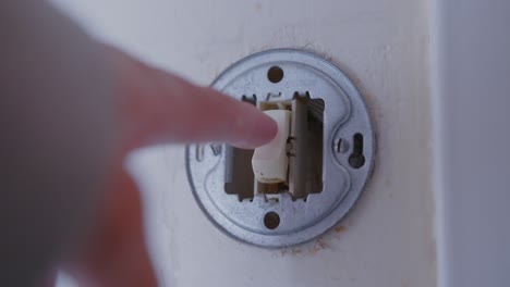 person turning on light switch on the wall