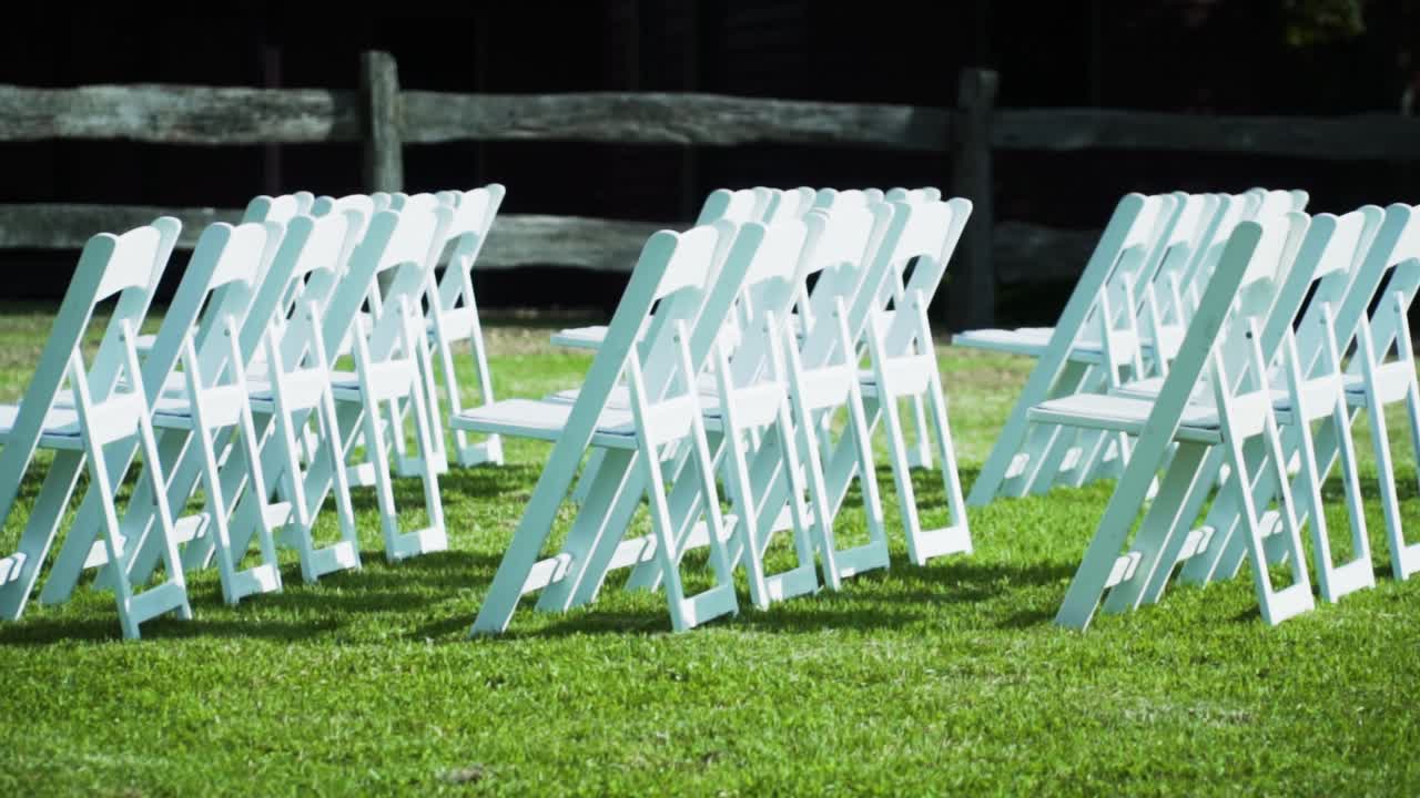 ajuste de sillas plegables para un evento de boda al aire libre con valla de madera en el fondo