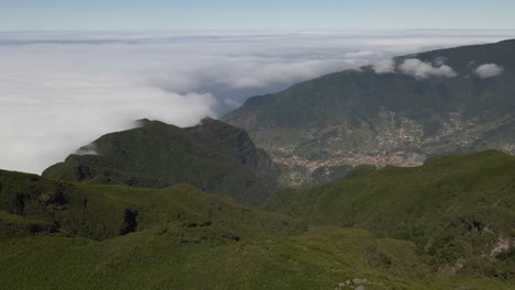 Flying-above-the-clouds-and-the-green-mountains-of-Madeira-island,-drone-flying-forward-revealing-the-parish-of-Sao-Vicente-in-Madeira-island,-view-from-Paul-da-Serra