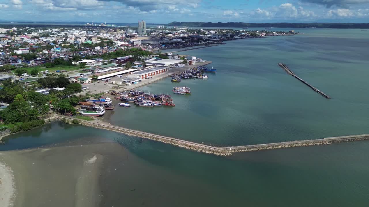 Vista aerea di Iloilo City che mostra la costa tropicale e lo skyline urbano sotto nuvole drammatiche. Porto con barche all'ancora, sviluppo costiero e vibrante atmosfera di città filippina dall'alto.