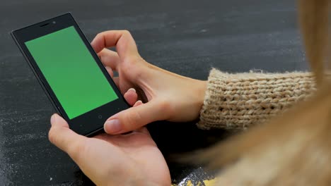 mujer usando un teléfono inteligente con pantalla verde