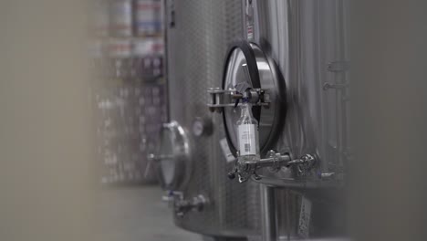 Peeking-through-Brewing-Equipment-at-a-Brewery-Fermenter,-Rack-Focus-Pan-Framed---30-fps