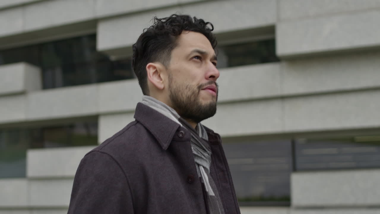 hombre guapo pensativo con una ligera positividad y esperanza camina por el distrito comercial del centro