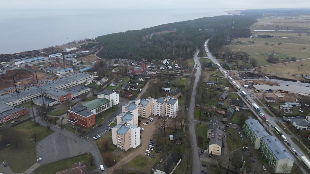 Aerial photograph of Salacgrīva, a coastal city in Latvia, featuring residential buildings, industrial areas, and a riverbank. Ideal for urban or geographical studies.