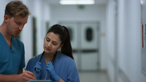 indian woman doctor consulting man surgeon in hospital corridor close up.