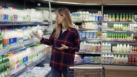 woman shopping in supermarket using smart phone, checking shopping list