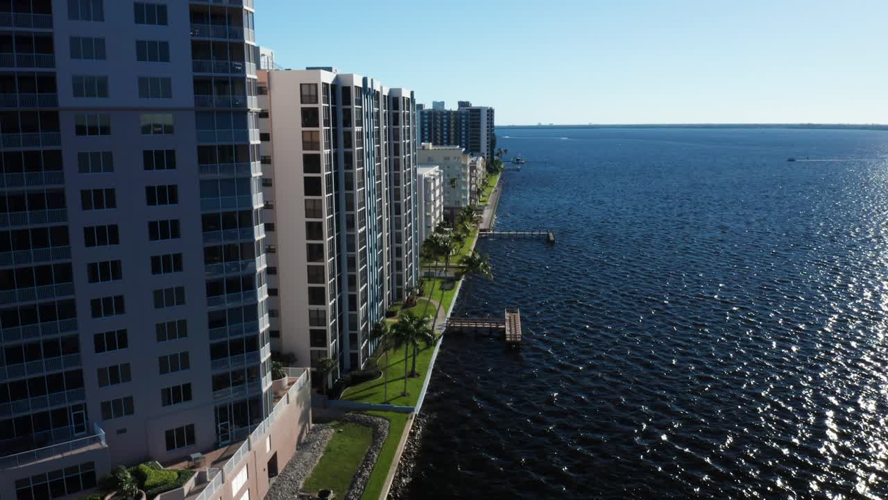 Apartemen bertingkat tinggi berjejer di sepanjang promenade tepi sungai dengan dermaga yang membentang di atas air. Ideal untuk gaya hidup perkotaan atau pemasaran properti.