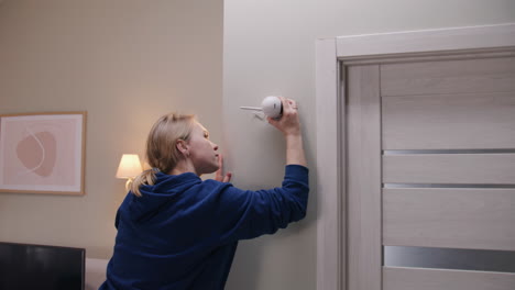 una mujer instalando una cámara de seguridad.