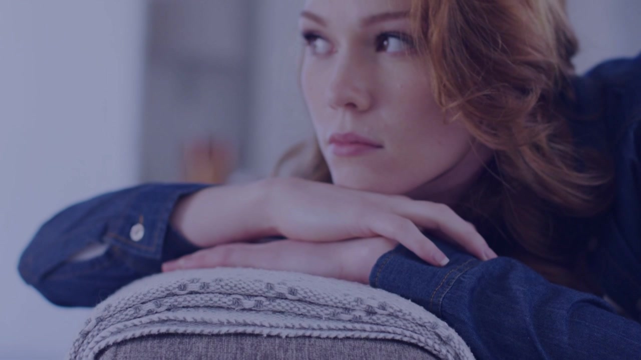Seated woman leaning on couch armrest, phone alerts spawning badges framing face for tech demo