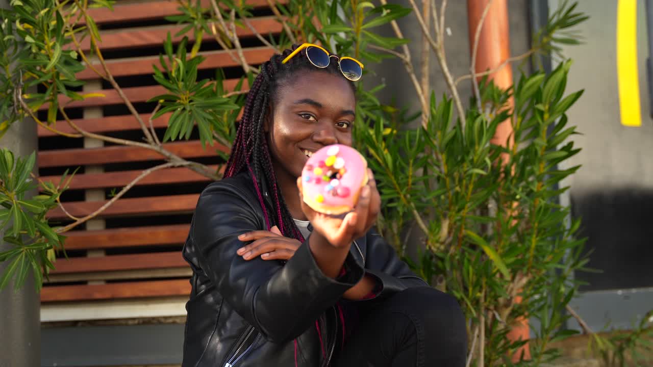 A fashionable woman enjoying a donut outdoors