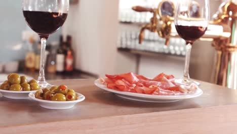 glass of red wine and snacks on bar counter